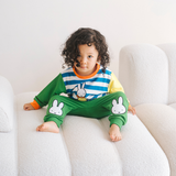 Bambino che indossa il completo da casa in bambù Miffy della linea Move, composto da felpa con motivo di bicicletta e pantaloni da jogging verdi