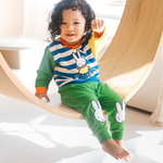 Bambino che indossa il completo da casa in bambù Miffy della linea Move, composto da felpa con motivo di bicicletta e pantaloni da jogging verdi