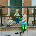Bambino che indossa il completo da casa in bambù Miffy della linea Move, composto da felpa con motivo di bicicletta e pantaloni da jogging verdi